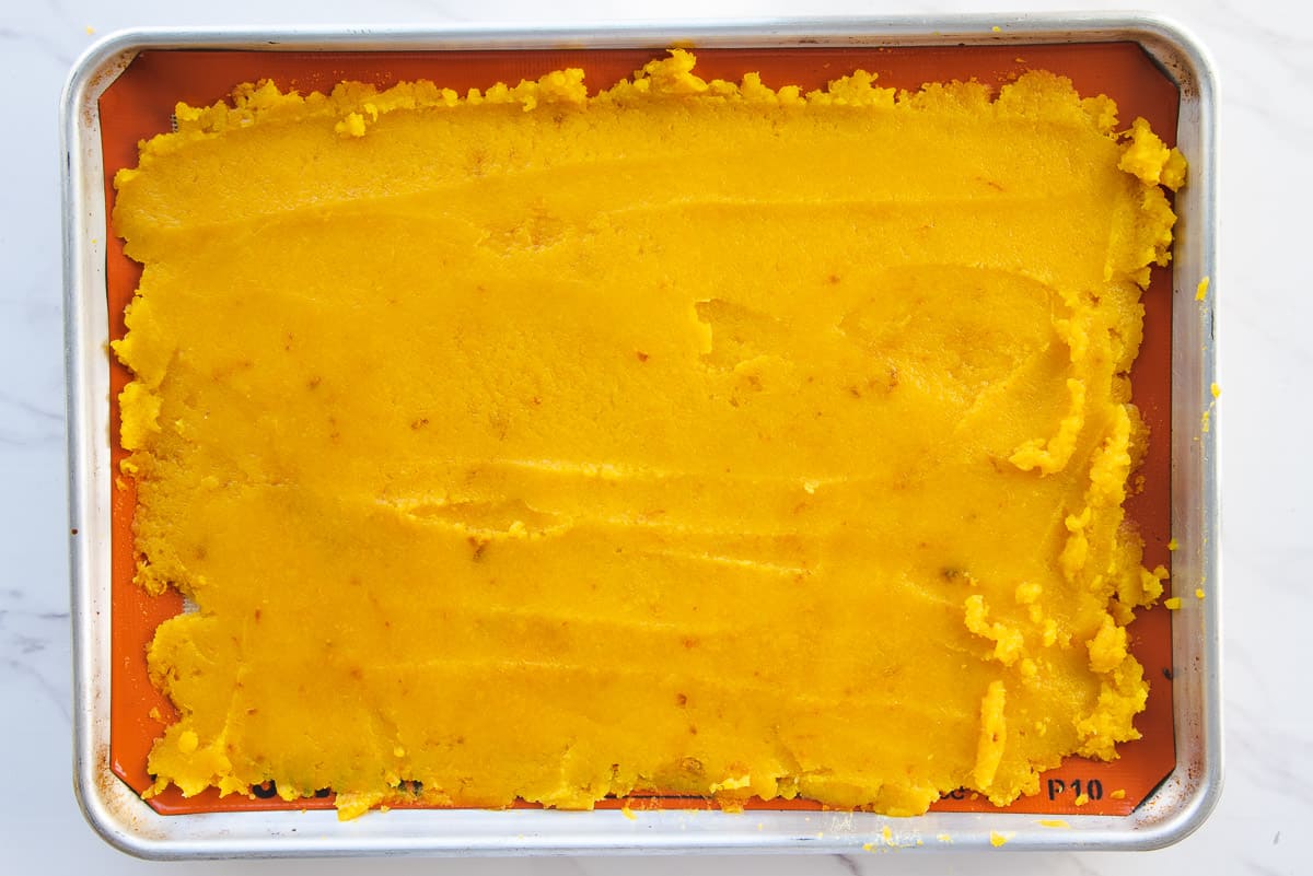 The pumpkin puree is smoothed out on a sheet pan.