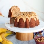A piece of Maple Walnut Banana Bundt Cake is lifted from the cake.