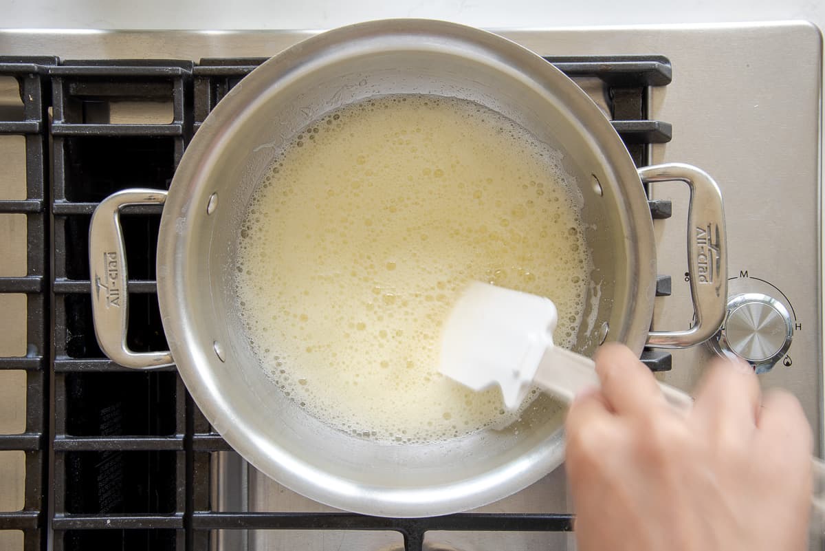 Butter is melted before being browned in a silver pot.