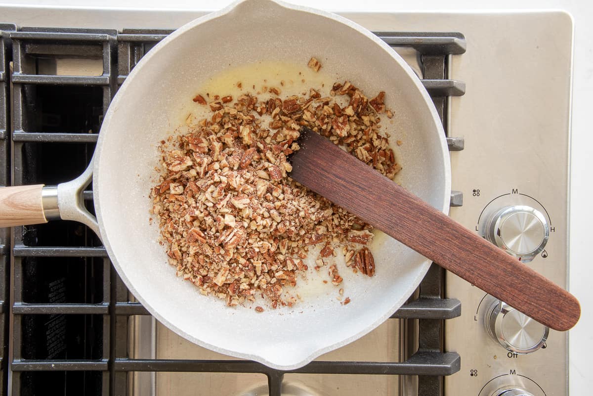 The chopped pecans are stirred into the melted butter.