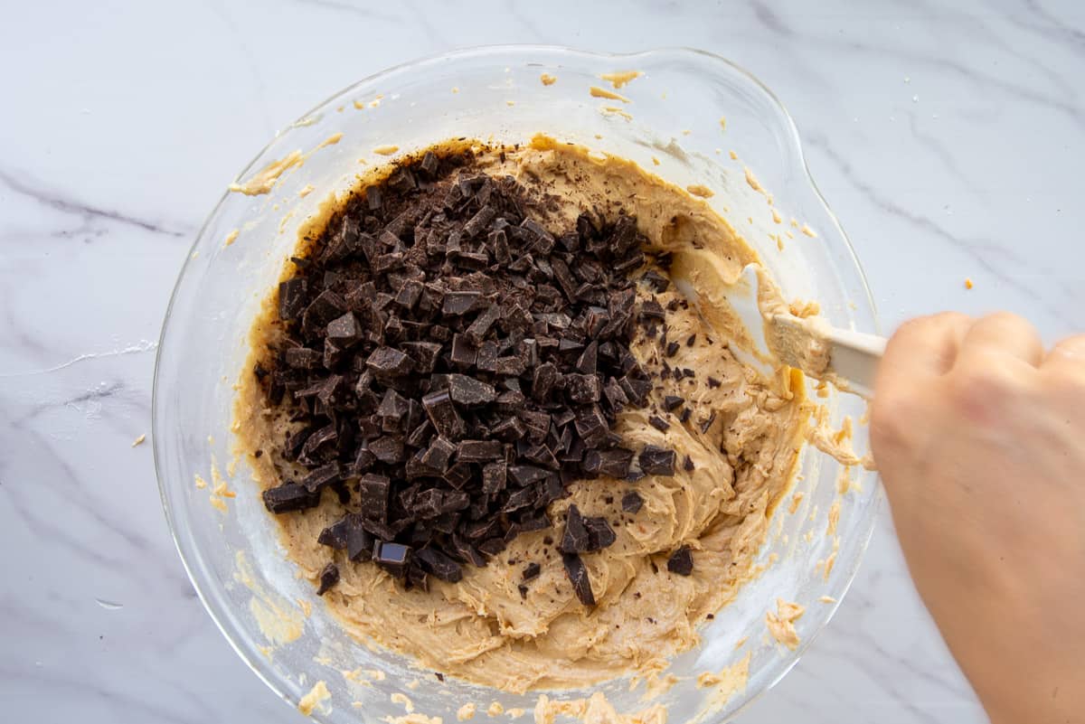 Chopped chocolate is folded into the batter in a clear, glass container.