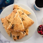 The Cranberry Ginger Scones are stacked in a pile on a marble cake stand.