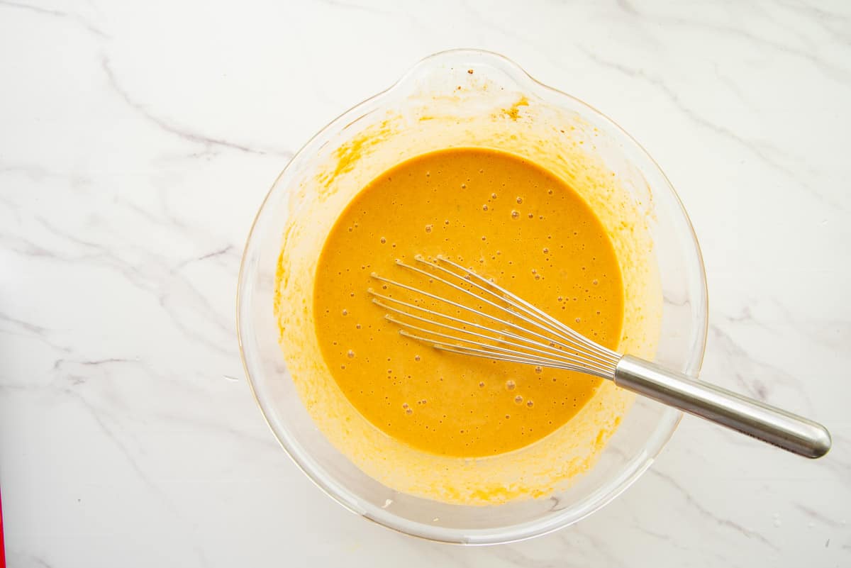 The custard is whisked together in a clear glass mixing bowl.