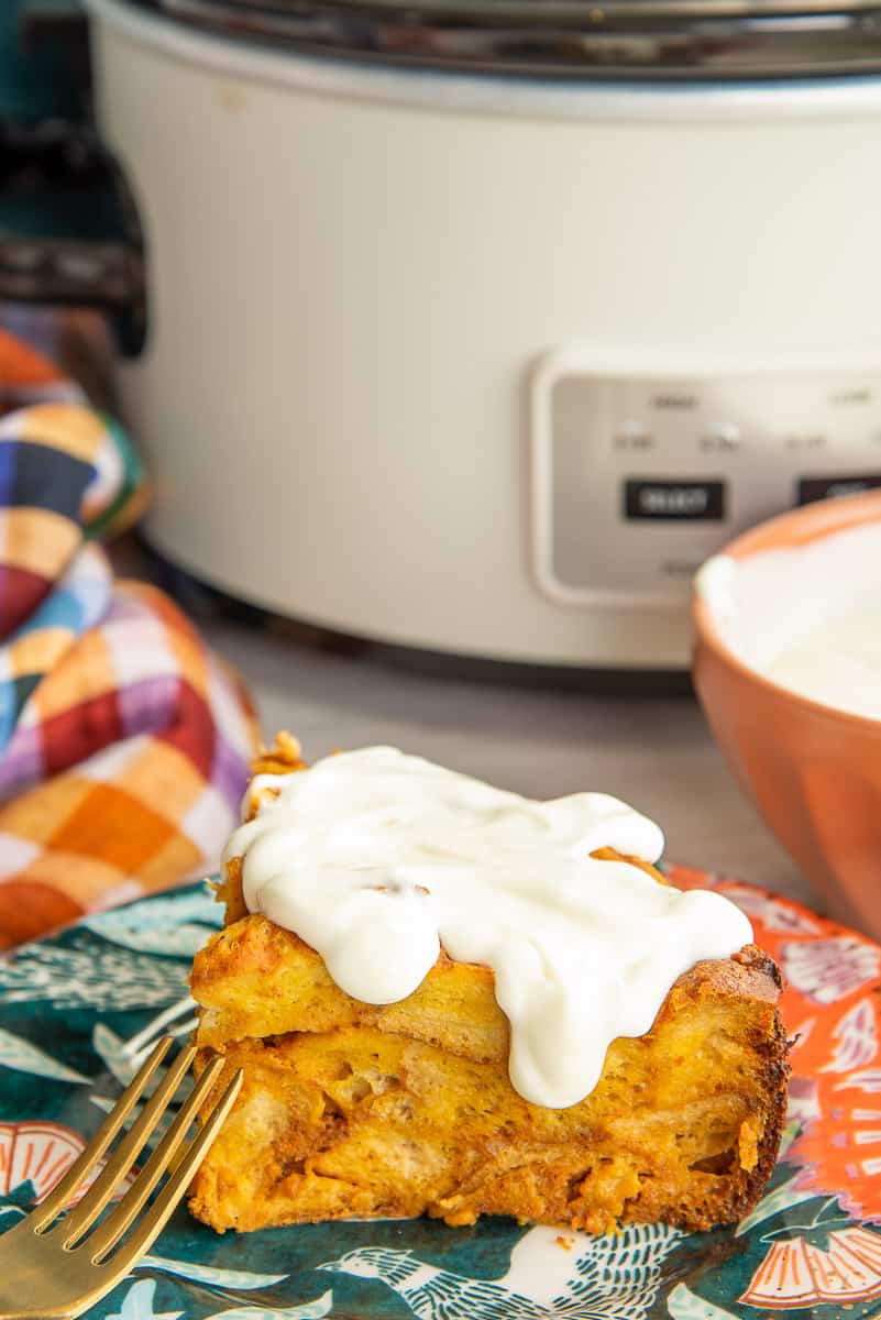 Cream Cheese Glaze drips down the side of a serving of Slow Cooker Pumpkin French Toast.