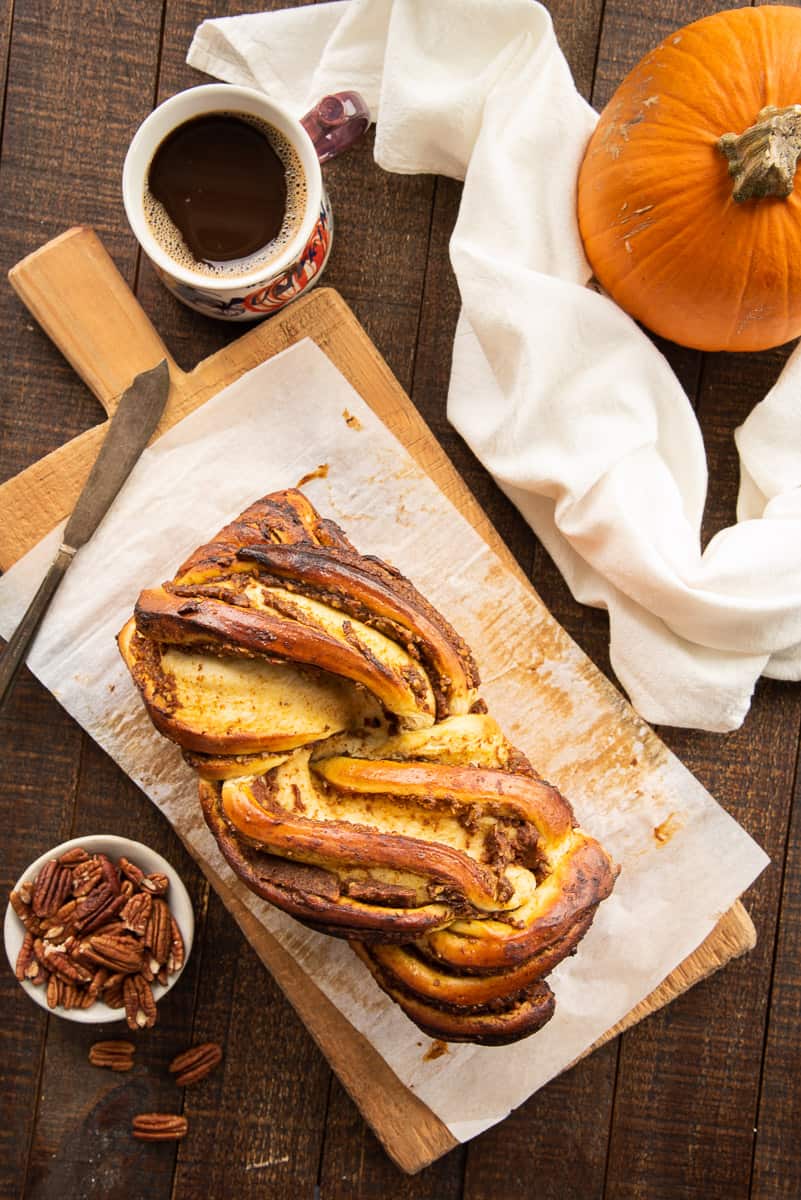 An overhead view of the baked loaf of Pumpkin Pecan Babka on a wooden cutting board.