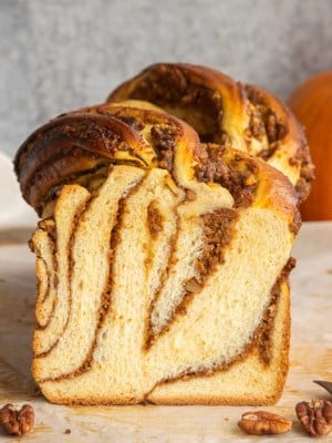 A loaf of Pumpkin Pecan Babka is sliced to reveal its interior.