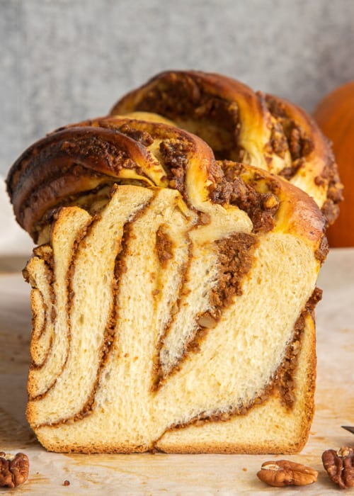 A loaf of Pumpkin Pecan Babka is sliced to reveal its interior.