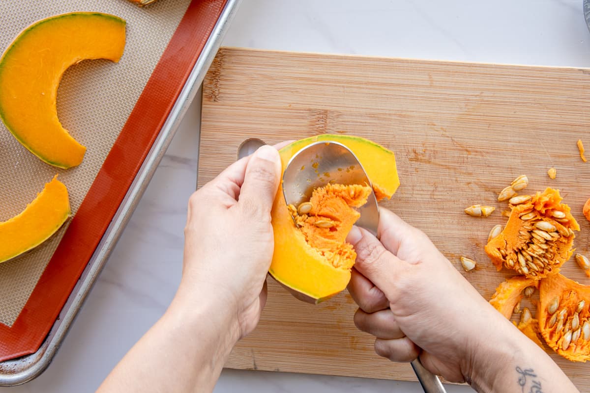 A wide spoon is used to scrape the seeds and insides from the slices of calabaza.