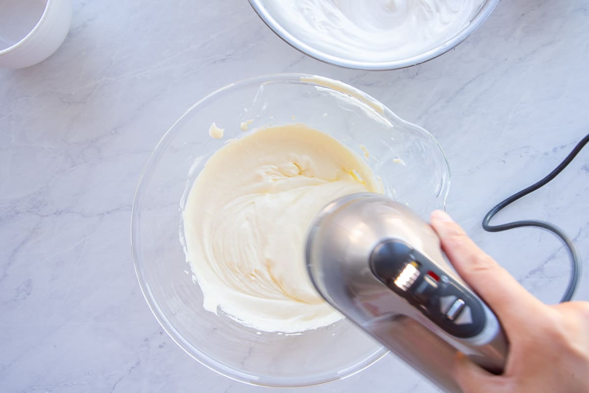An electric hand mixer whips the egg yolks until fluffy.