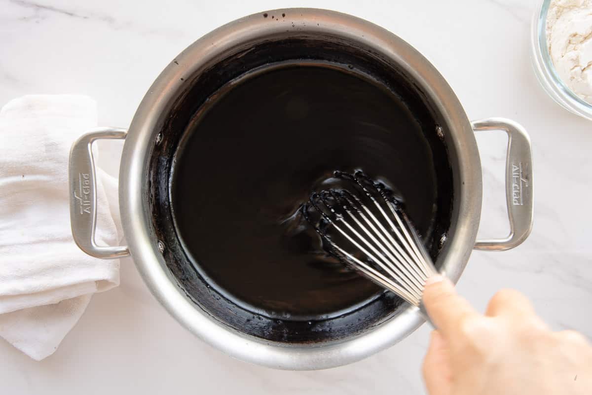 The liquids are added to the pot with the rest of the ingredients with a silver whisk.