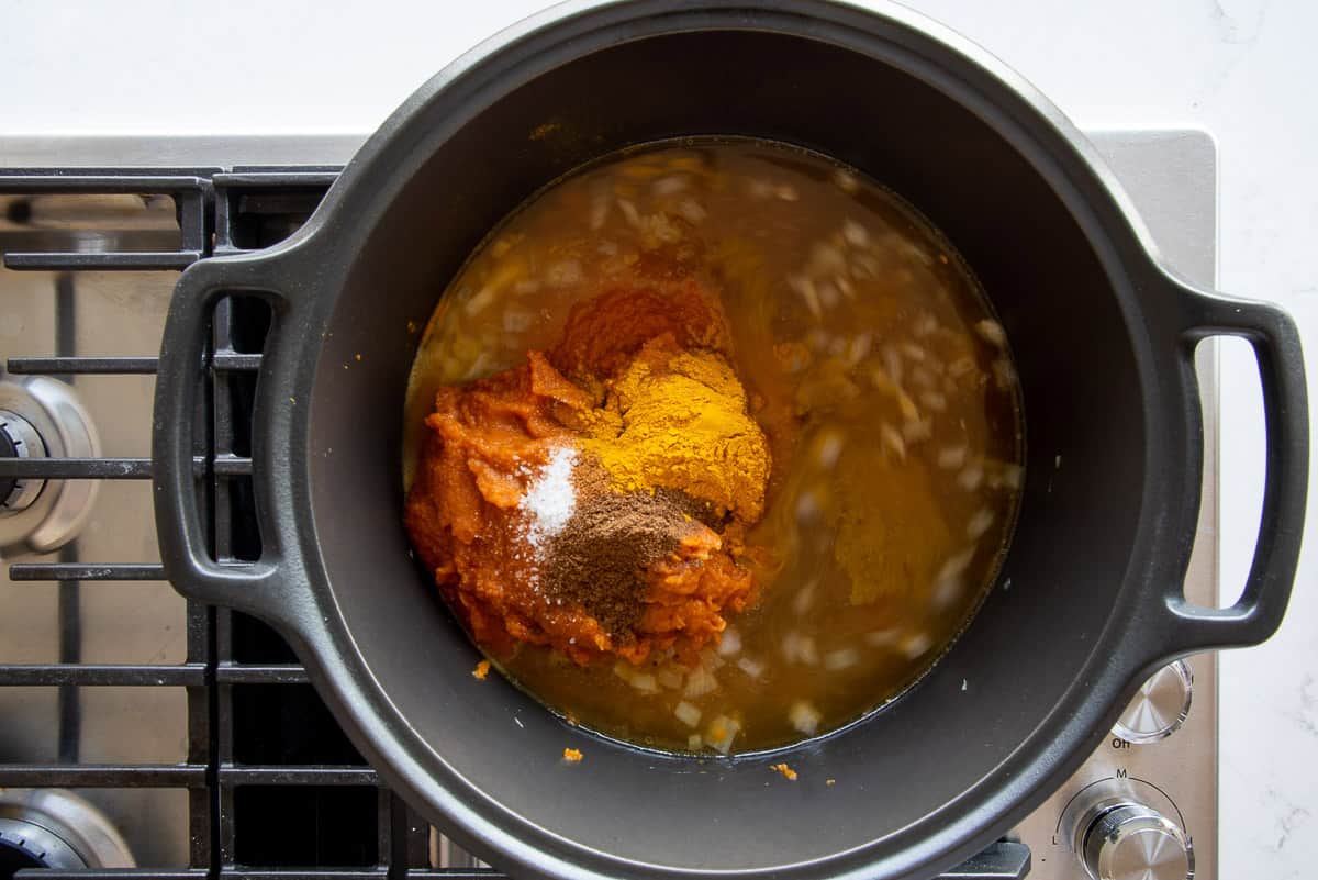 The pumpkin and spices are added to the dutch oven with the vegetable stock.