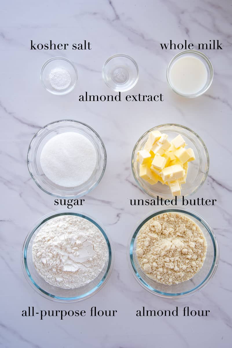 The ingredients to make the almond short dough are labeled on a white countertop.