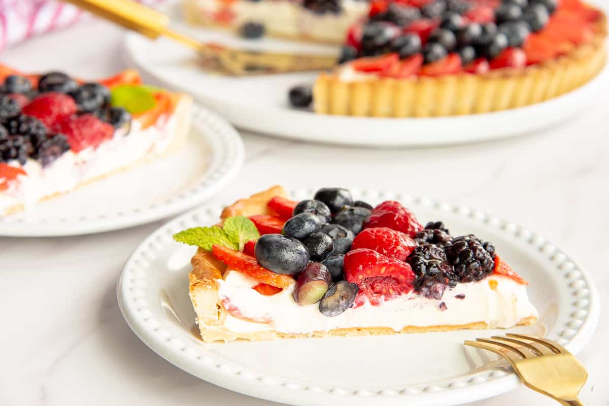 A sideview of a cut piece of the Mixed Berry Tart on a white plate.