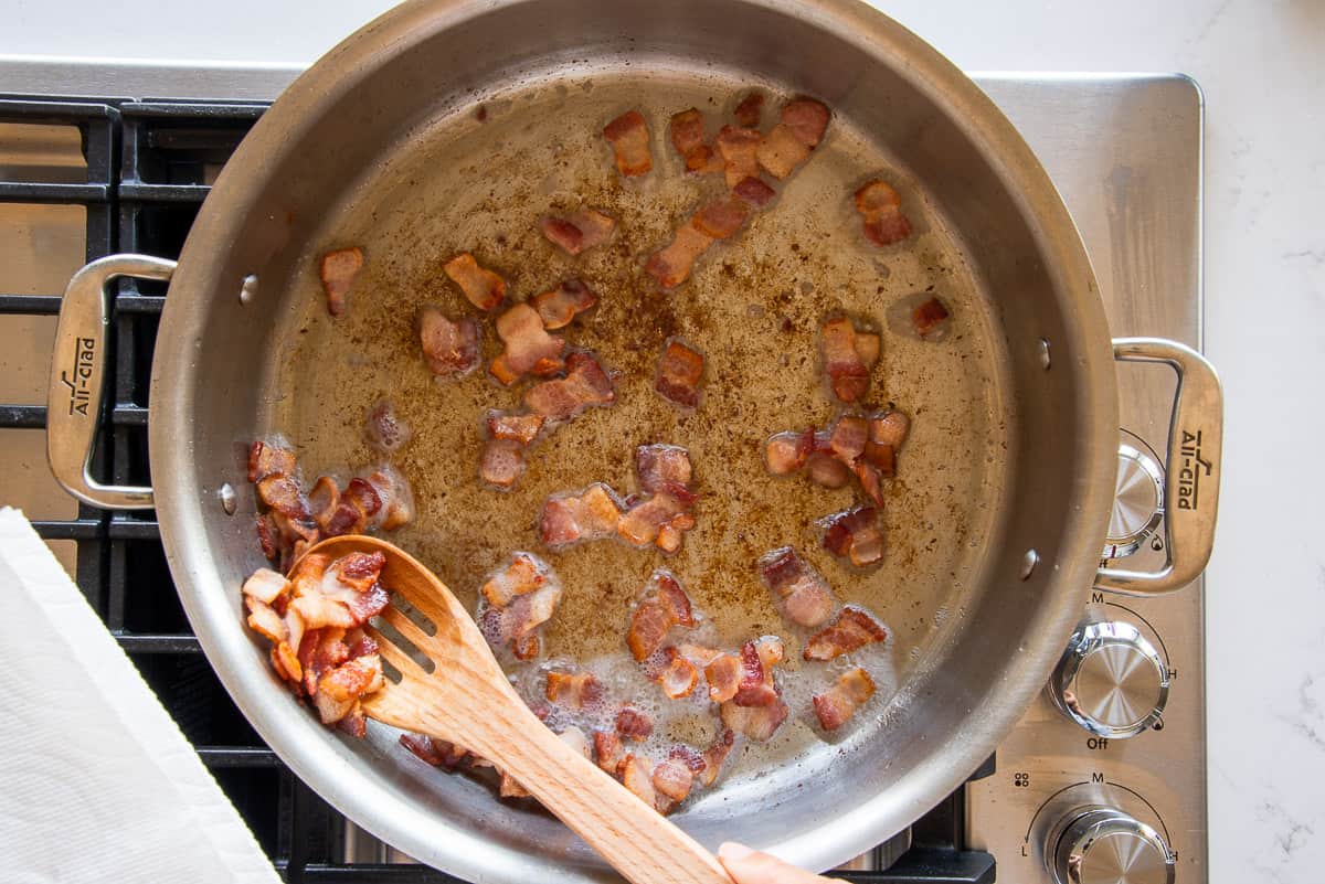 The crisp bacon pieces are removed from the pot with a slotted spoon.