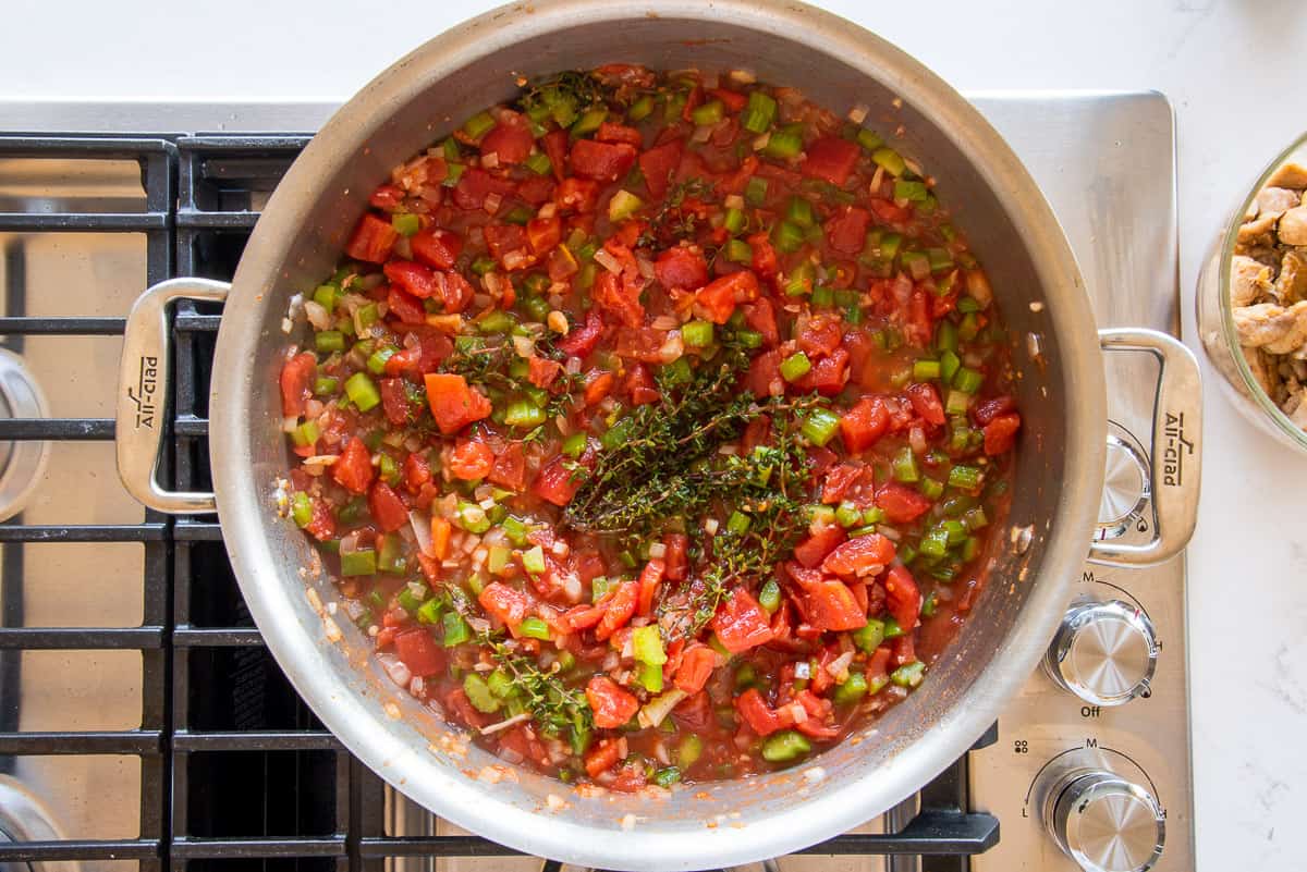 The tomatoes, and herbs are added to the pot with the aromatics.