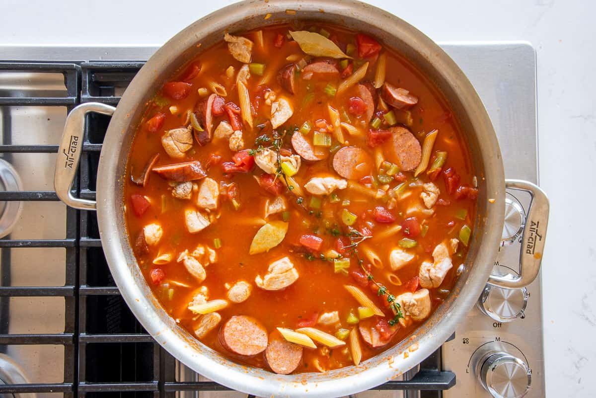 Seafood stock, pasta, and meats are added to the pot with the rest of the ingredients.