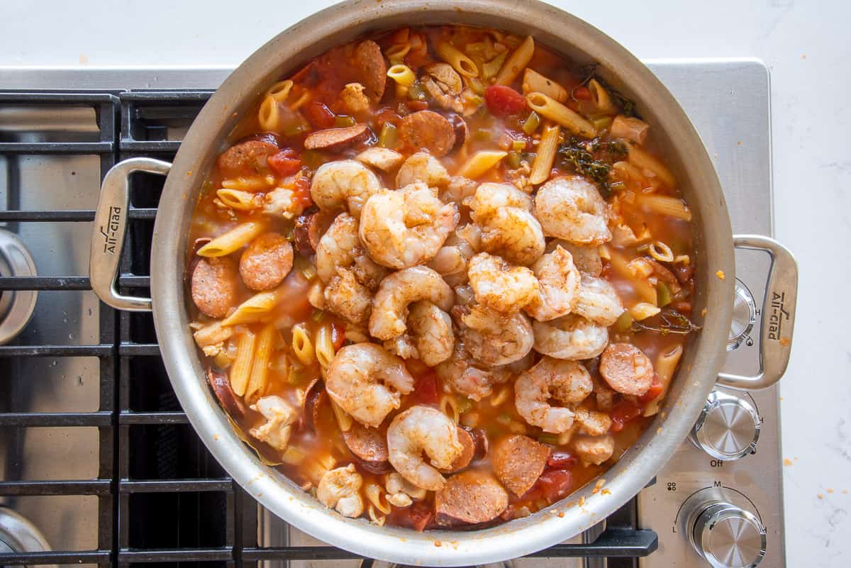 The shrimp is added to the rest of the ingredients in a wide silver sauté pan.
