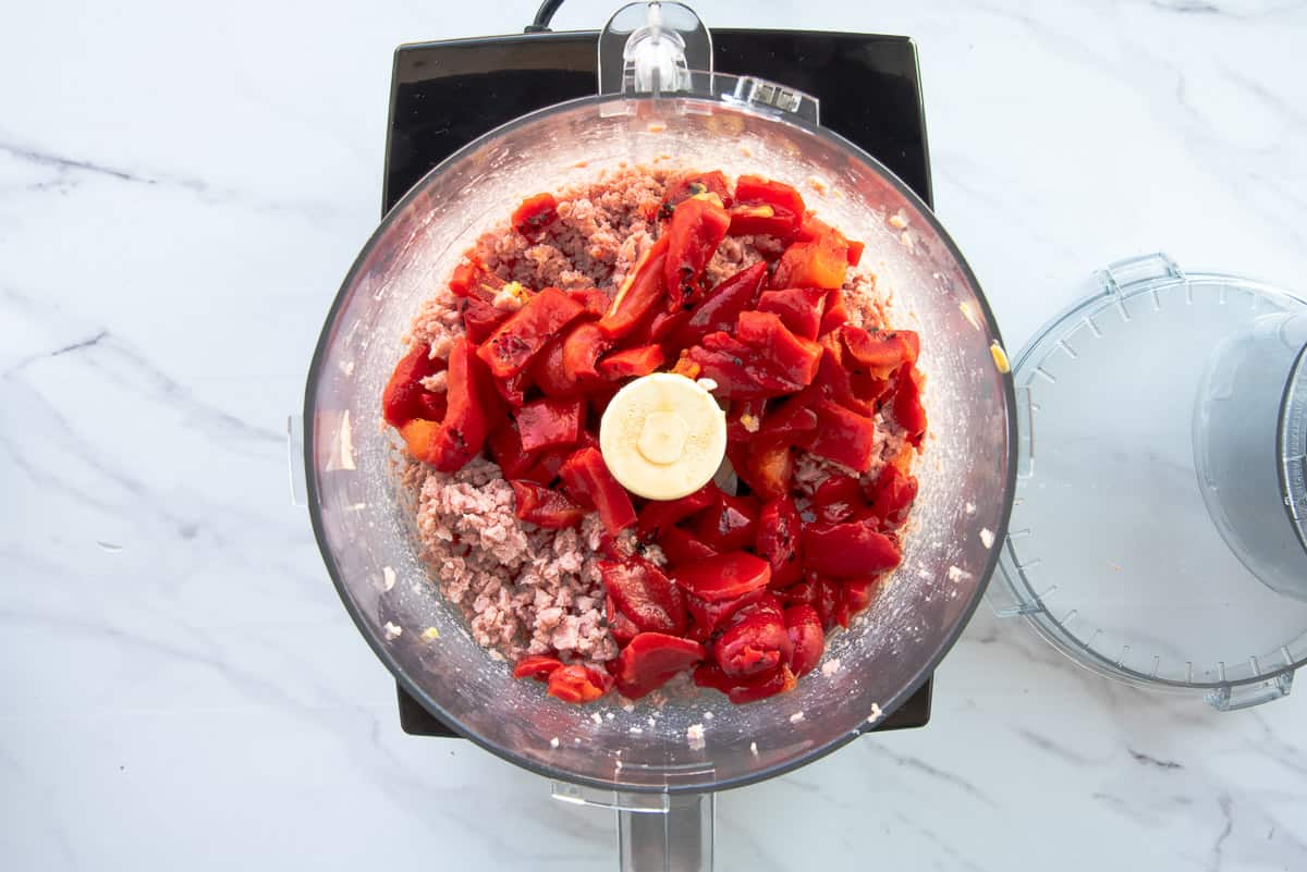The roasted red pepper is added to the food processor with the diced canned ham.