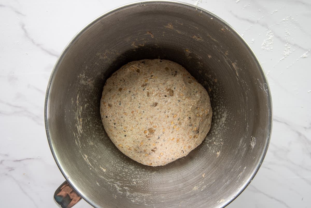 The ball of bread dough is set into a greased mixing bowl before proofing.