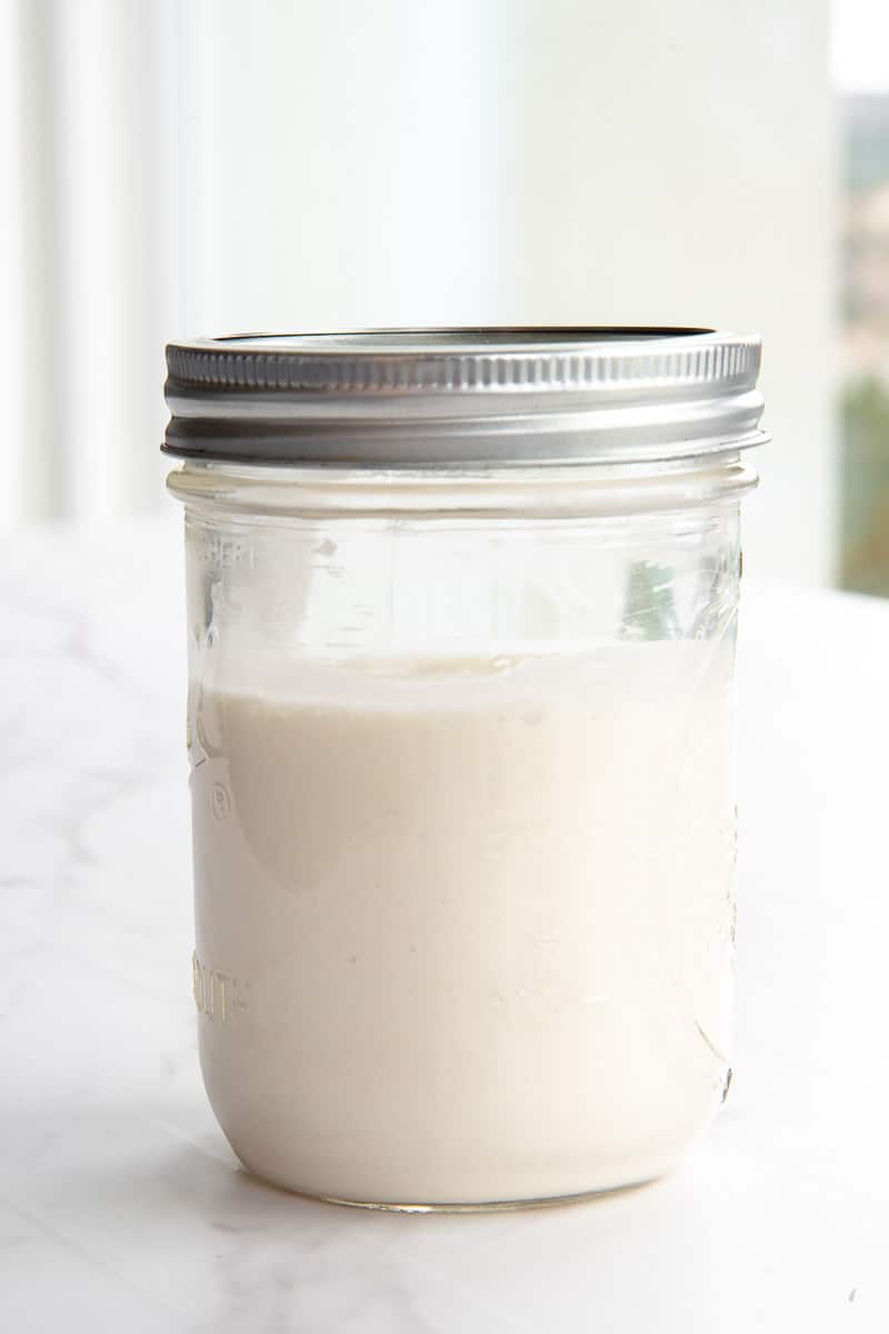 Sourdough Starter in a clear glass jar with a silver lid.