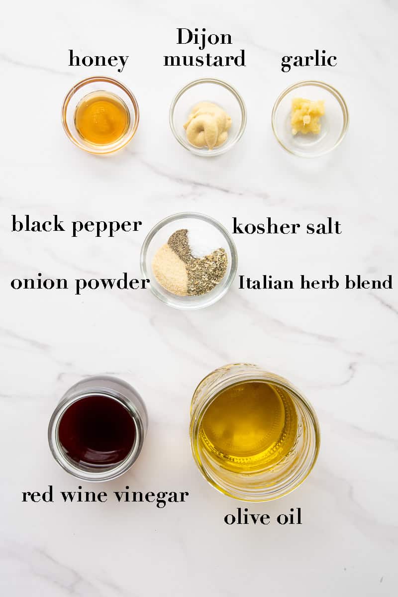 The ingredients needed to make the red wine vinaigrette on a white countertop.