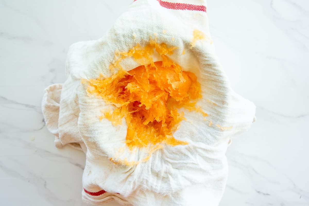 Shredded cantaloupe after being squeezed in a white kitchen towel.