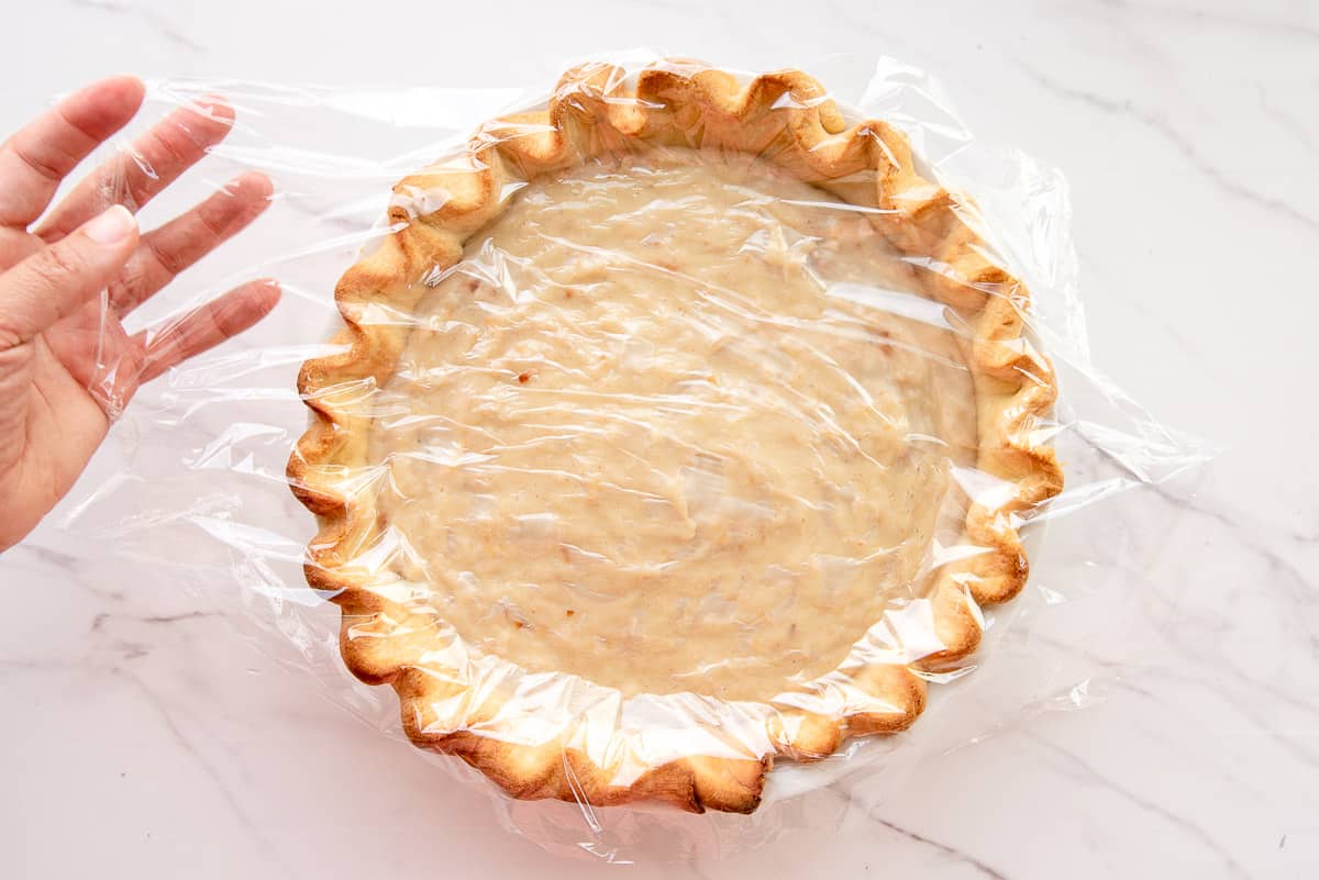 Plastic wrap is placed on the custard in the pie shell.