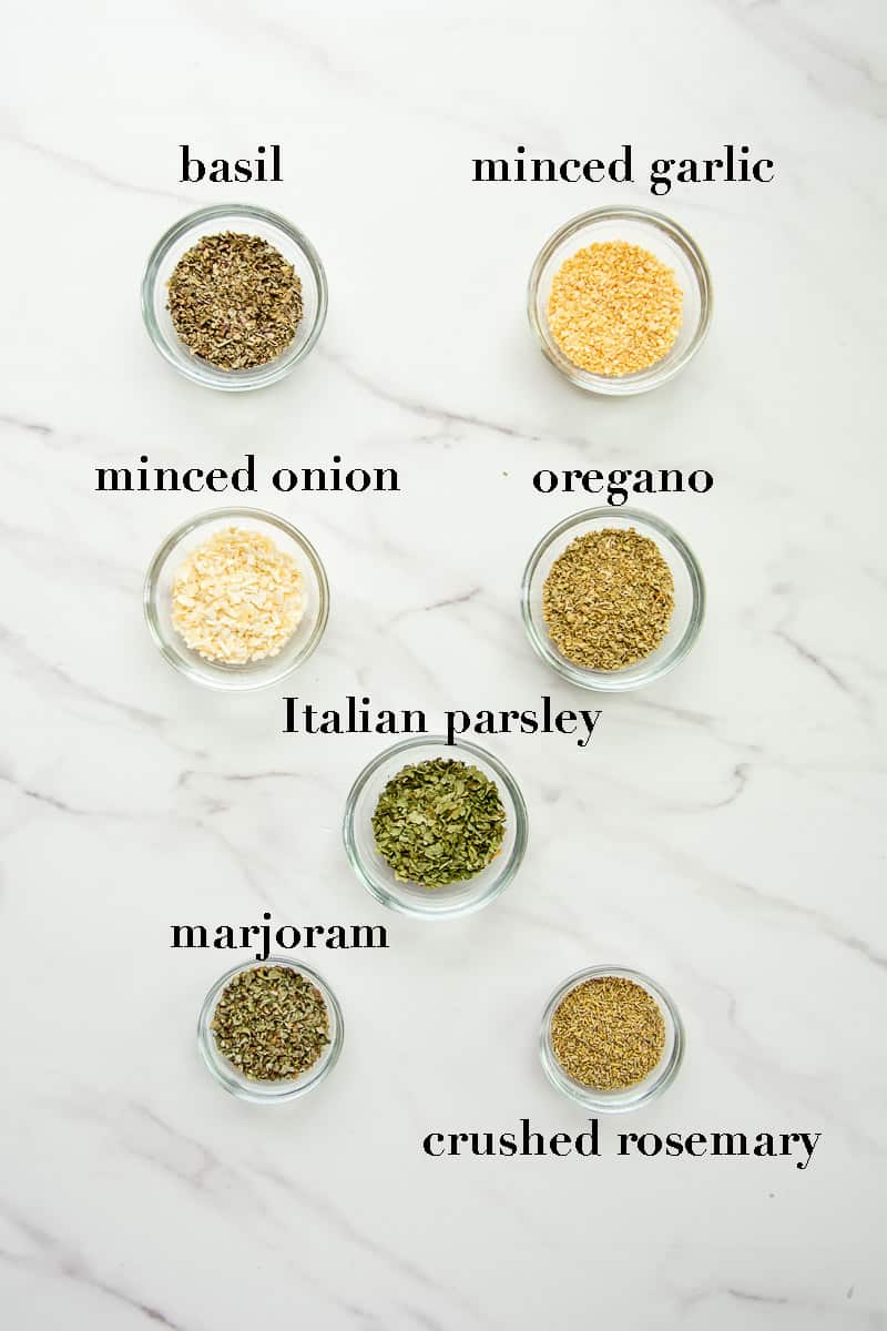 The ingredients needed to make Italian herb blend on a white countertop.