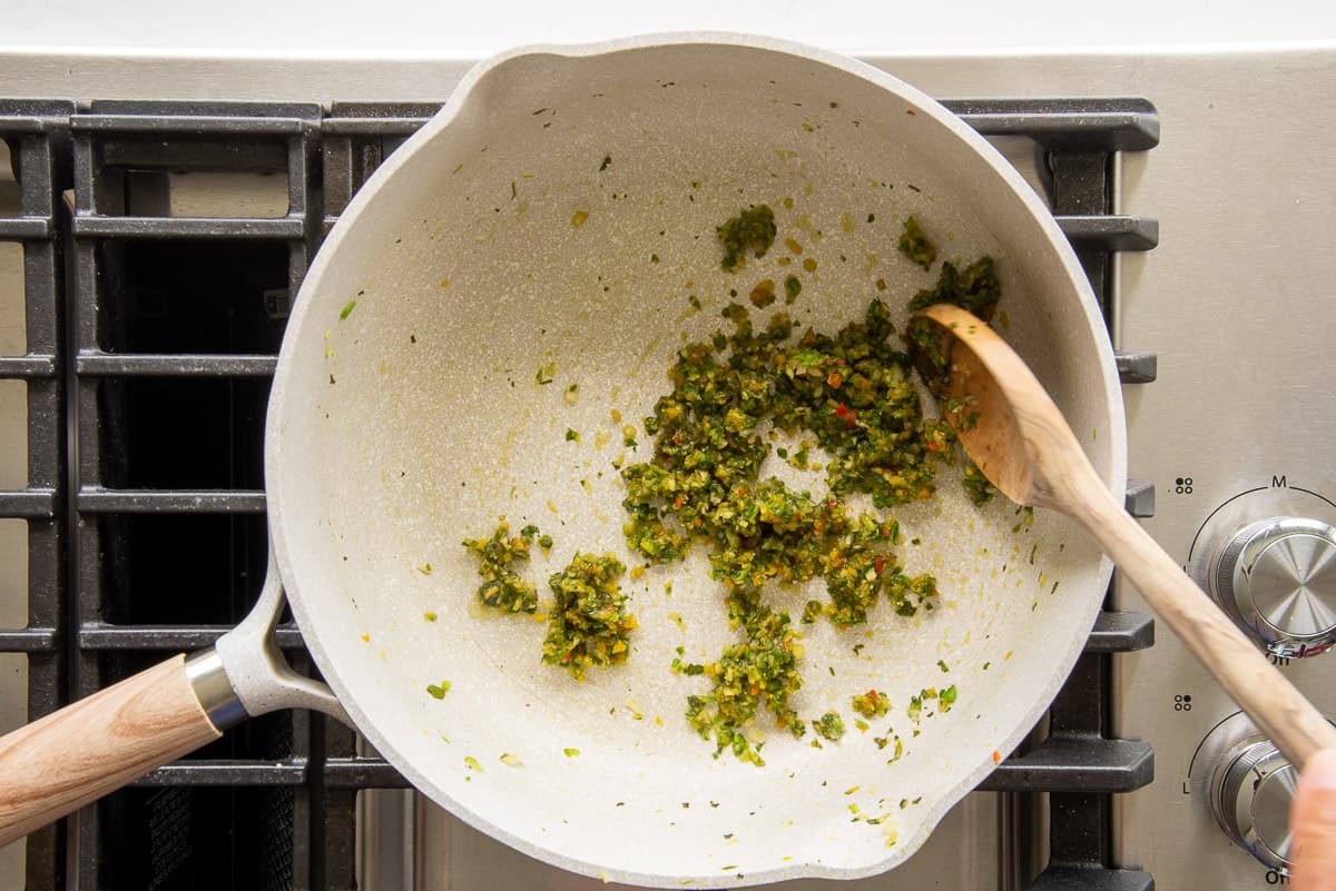 The sofrito is sauteed in a gray pan on the stove top.