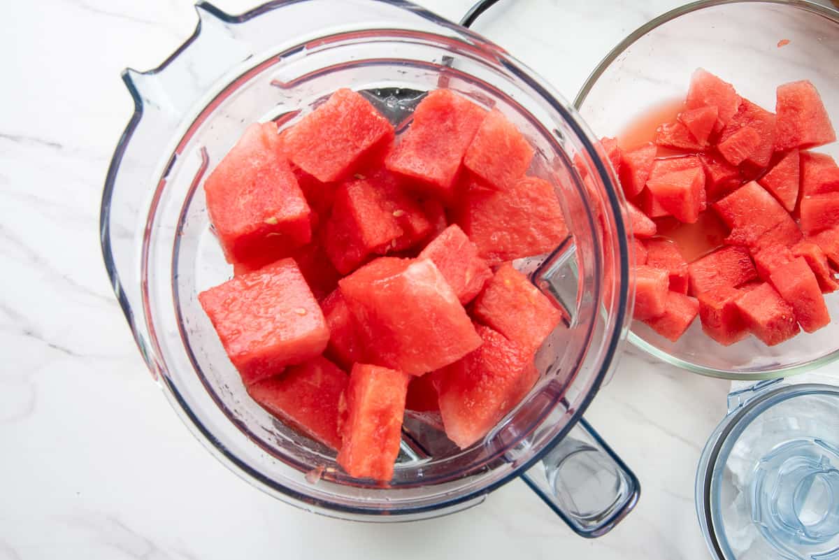Cubes of watermelon are added to a blender before being pureed.