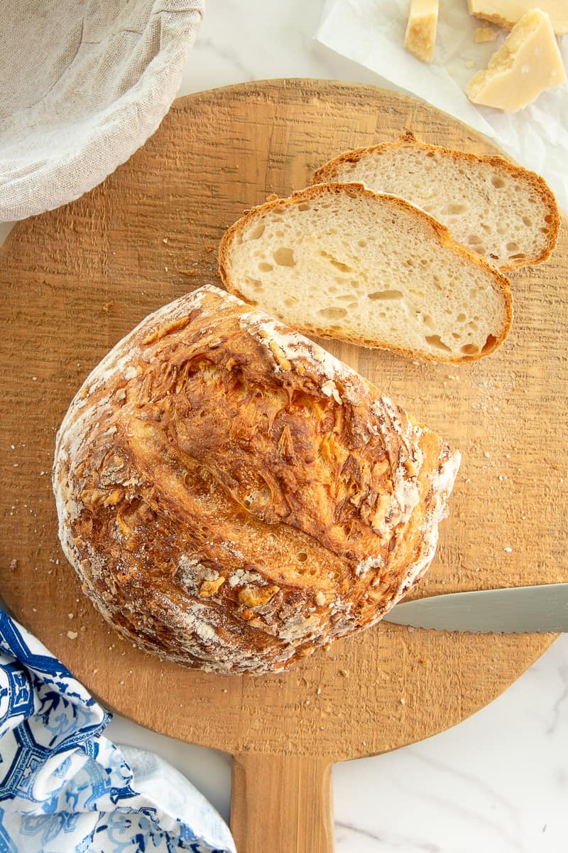 A round loaf of Asiago Sourdough Bread with two slices cut.