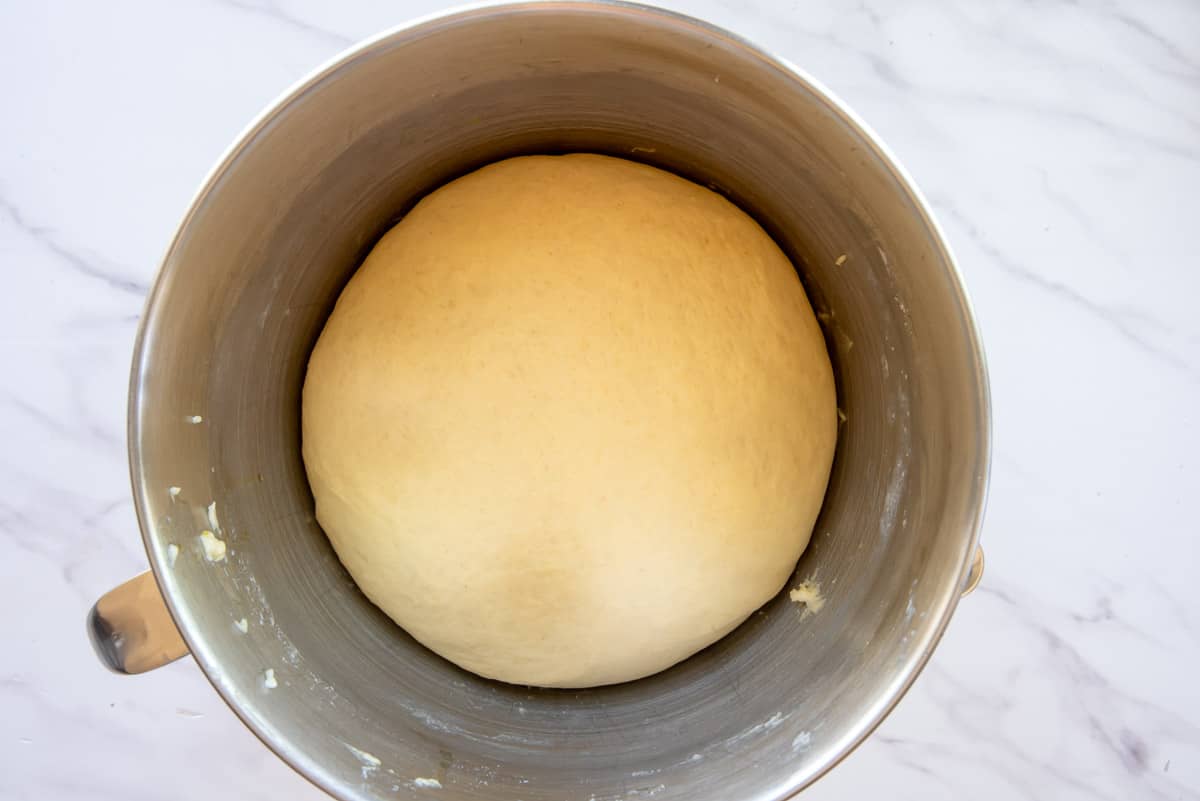The dough in a silver mixing bowl after the first rise.