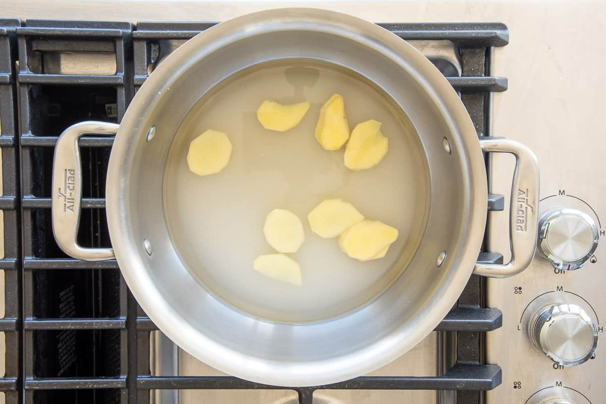 The ginger, sugar, and water are combined in a pot on the stove.