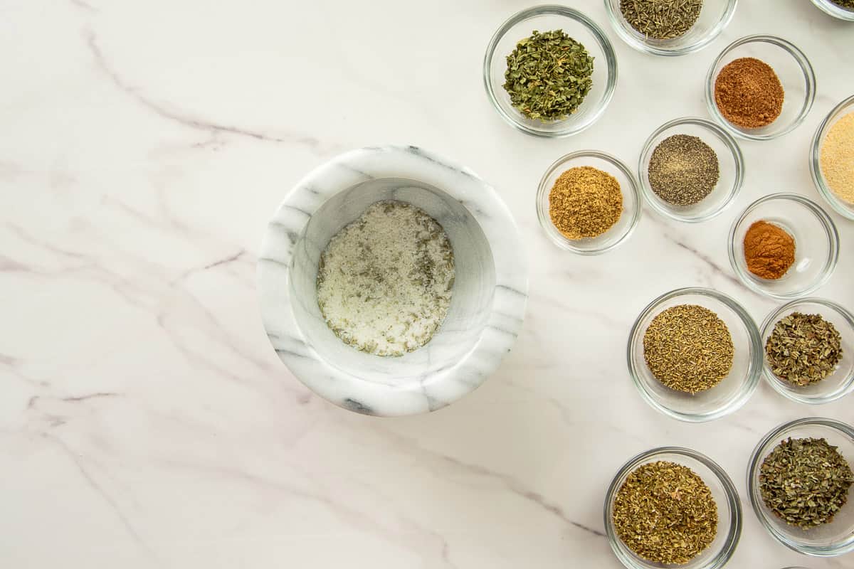 The fennel and kosher salt are ground in a mortar and pestle to make them finer.