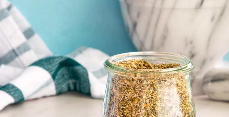 The finished Greek Seasoning Blend in a clear glass jar.