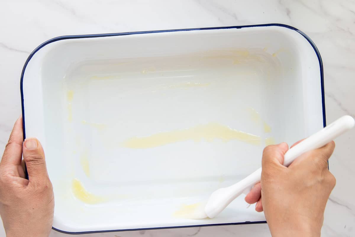 Melted butter is brushed into the baking dish.