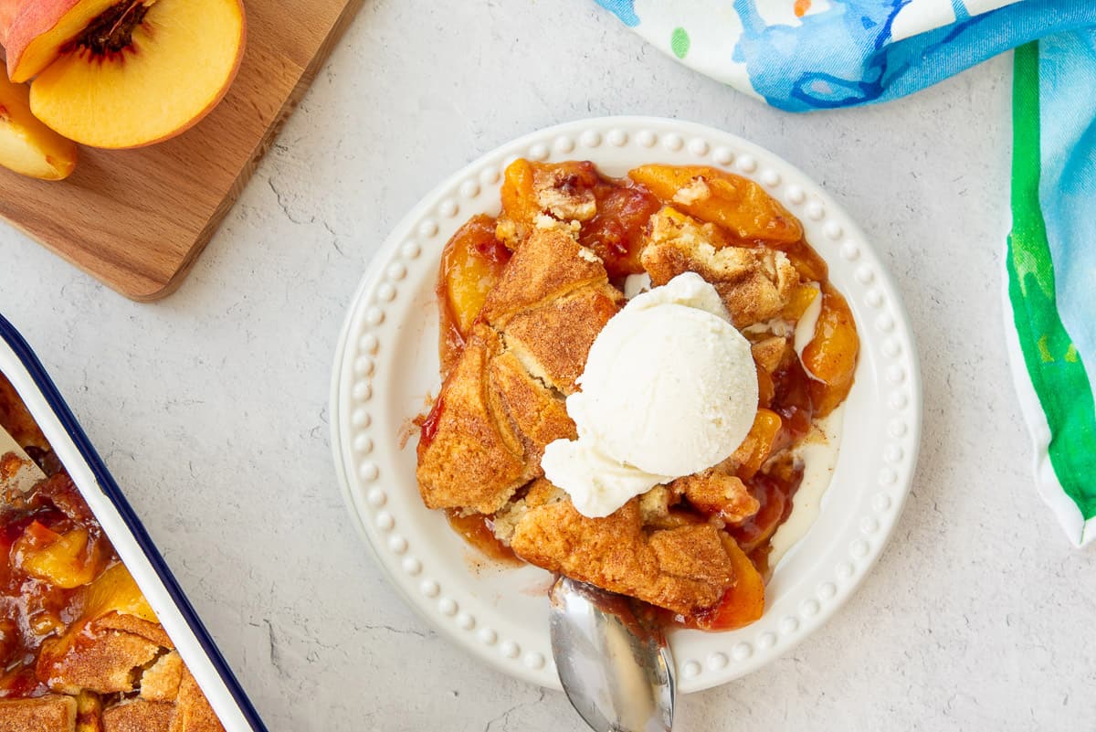 A serving of Homemade Peach Cobbler topped with ice cream.