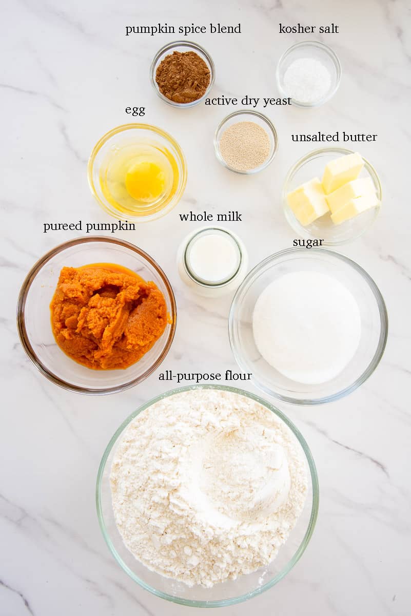 The ingredients needed to make the pumpkin roll dough are labeled on a white countertop.