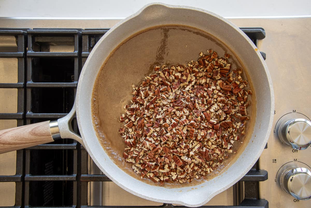 Chopped pecans added to a the pan with the maple caramel.