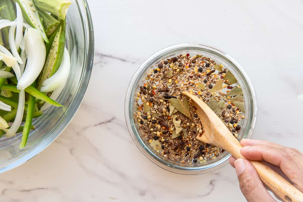 The vinegar and pickling spice blend are combined in a glass mixing bowl.