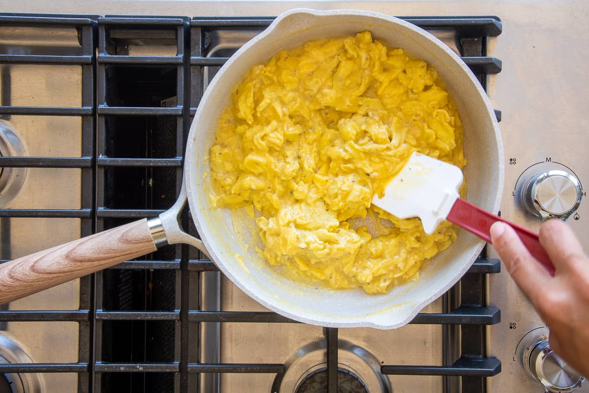 Eggs are scrambled in a skillet on the stovetop.