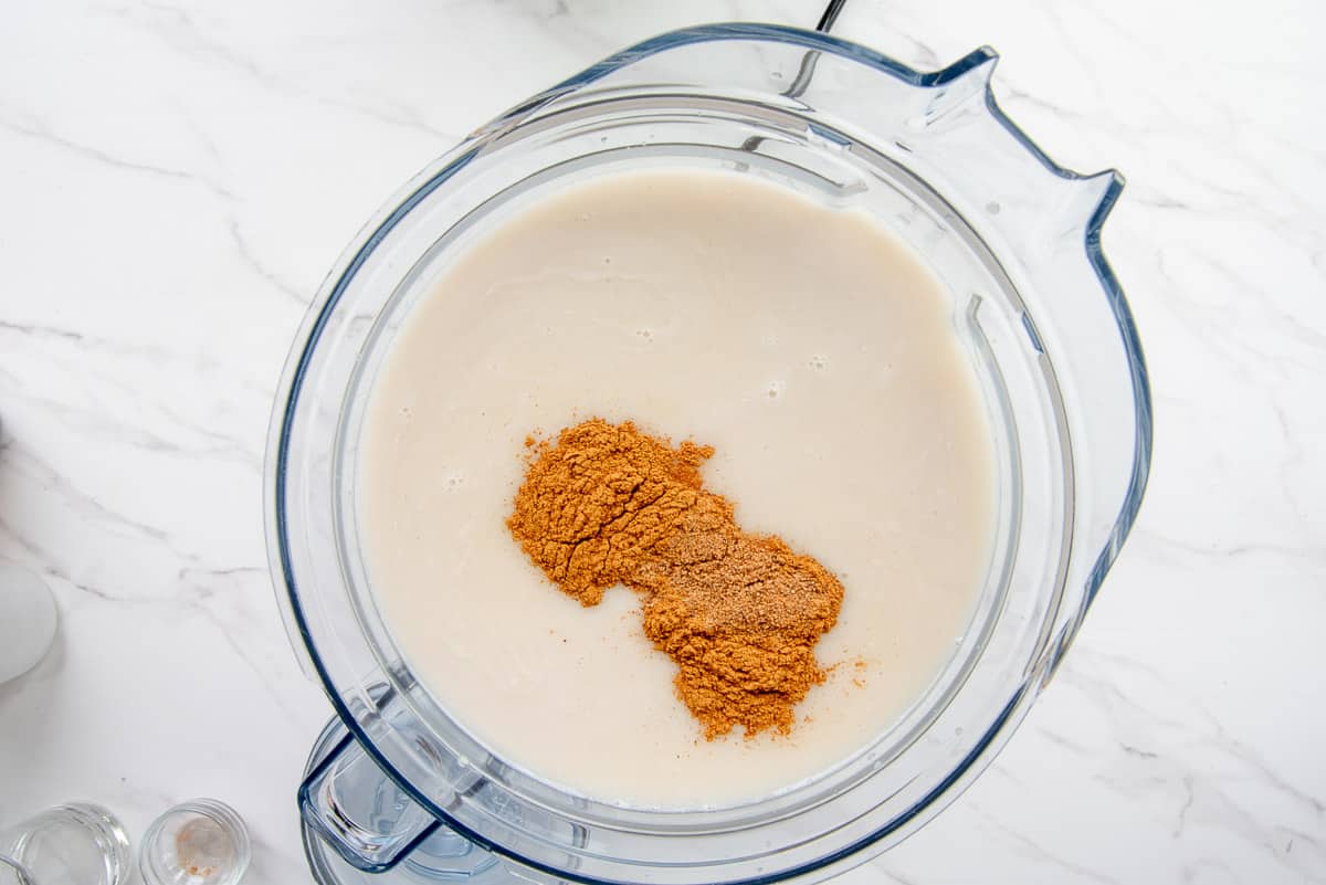 The remaining ingredients for the coquito are added to the blender along with the ground spices.
