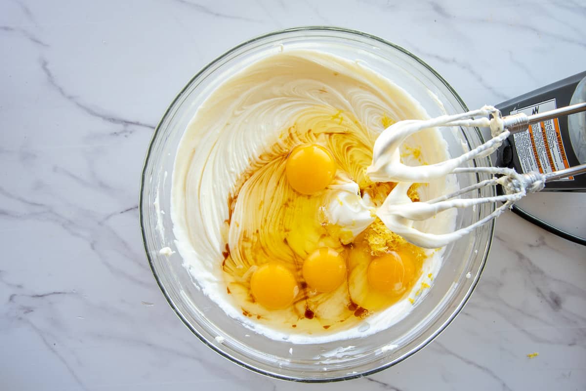 The eggs, lemon zest, and vanilla extract are blended into the cream cheese and sugar mixture with an electric hand mixer.