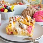 Concha Breakfast Bake on a white plate in front of a plate with multi-colored conchas and a mug of coffee.