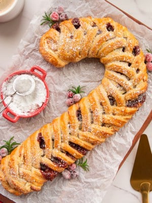 Guava Cream Cheese Candy Cane Pastry dusted with powdered sugar on a wooden cutting board.