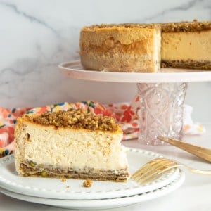 Honey Baklava Cheesecake on a stack of two white plates with a gold fork resting on the top plate.