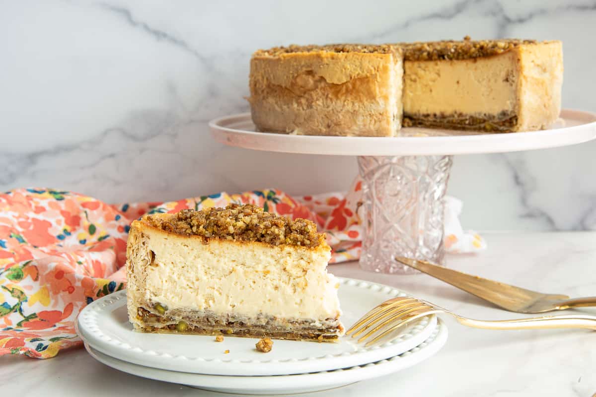 Honey Baklava Cheesecake on a stack of two white plates with a gold fork resting on the top plate.