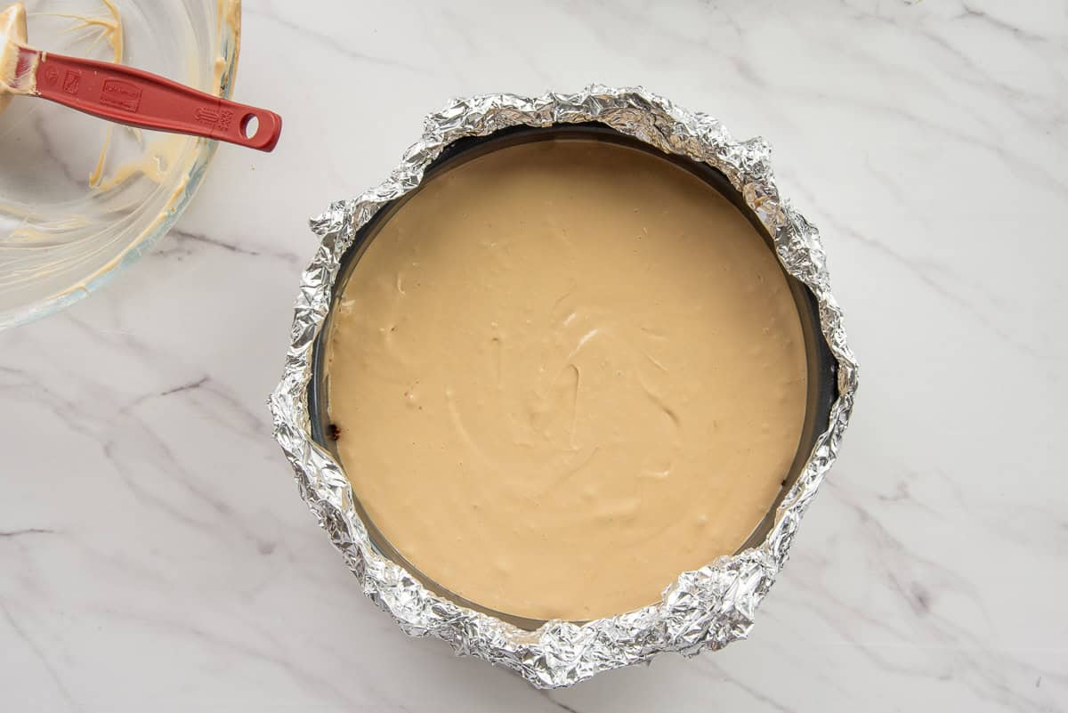 The cheesecake batter is poured into the foil-wrapped cheesecake pan.