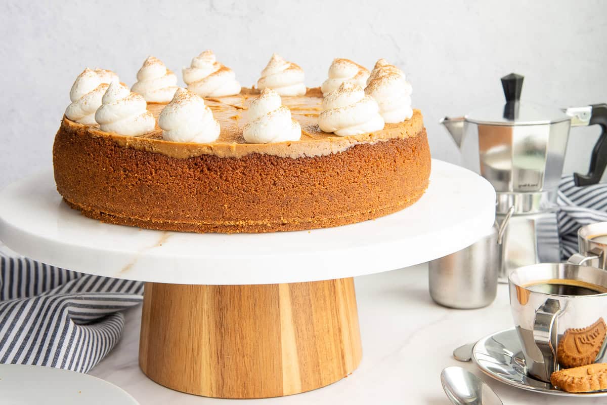 A side view of the Espresso Cheesecake with Biscoff Crust on a marble and wooden cake stand.