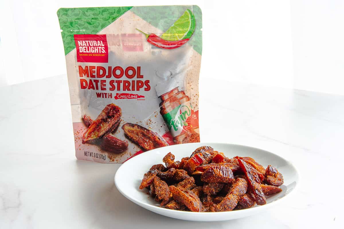 A bowl of date strips is on front of a bag of the strips.
